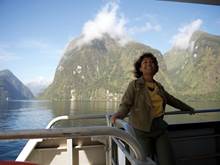 A woman leans against the back deck of a vessel cruising through Doubtful Sound