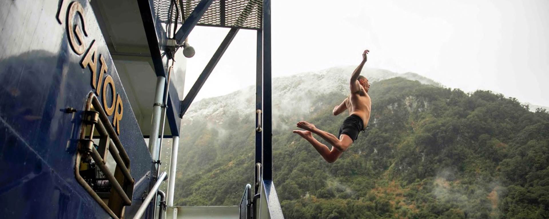 A man jumps off the back deck of the Fiordland Navigator into the water at Doubtful Sound 