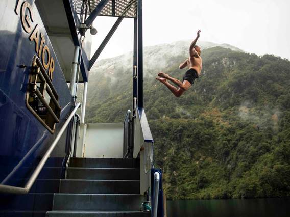 A man jumps off the back deck of the Fiordland Navigator into the water at Doubtful Sound 